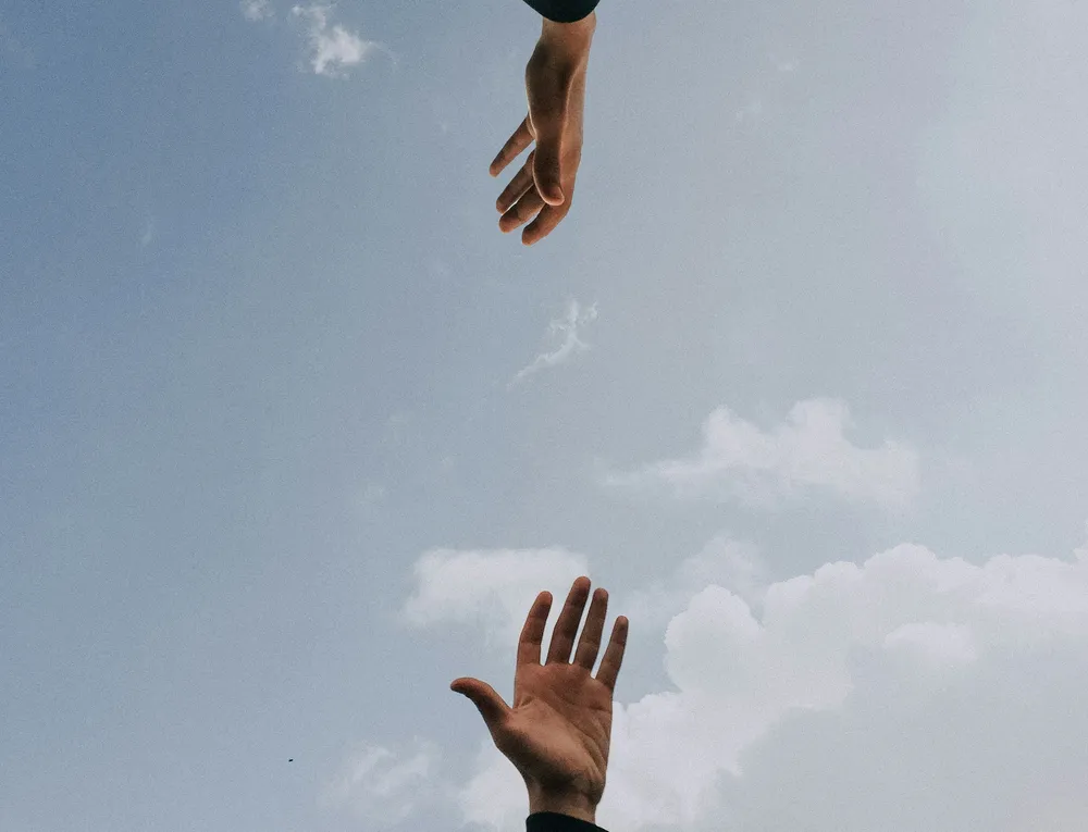 Symbolbild für Begleitung auf dem Weg zum Wunschkind Zwei ausgestreckte Hände vor hellem Himmel als Symbol für Begleitung und Unterstützung im Kinderwunsch